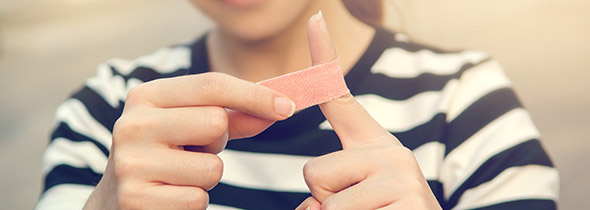 Photo : une jeune femme place un pansement sur son doigt
